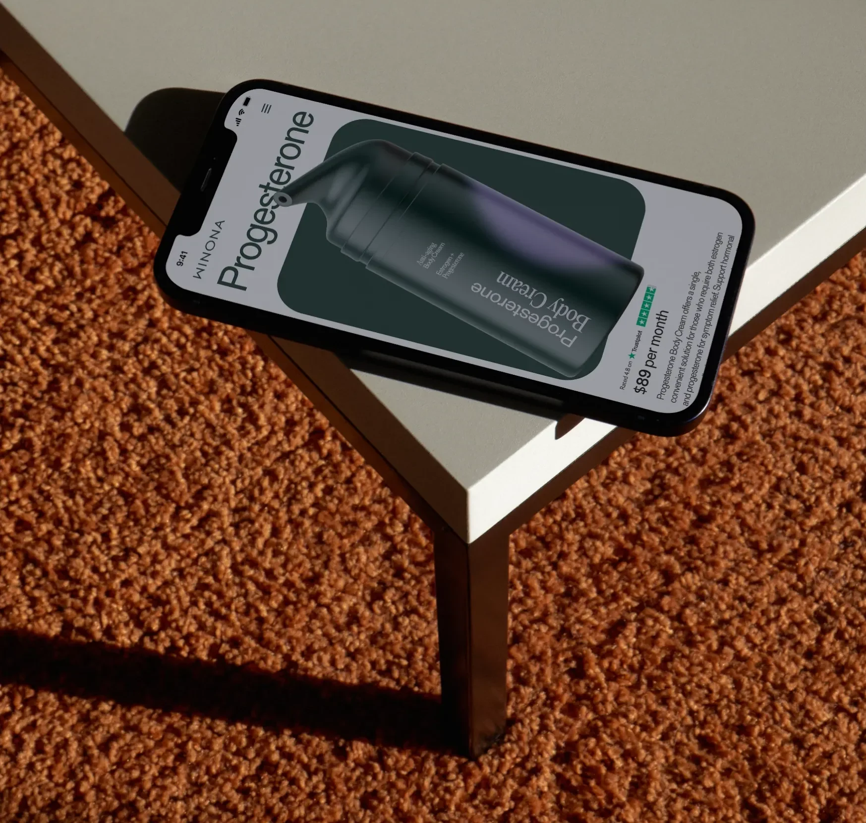 Winona progesterone body cream page on a phone resting on a table.