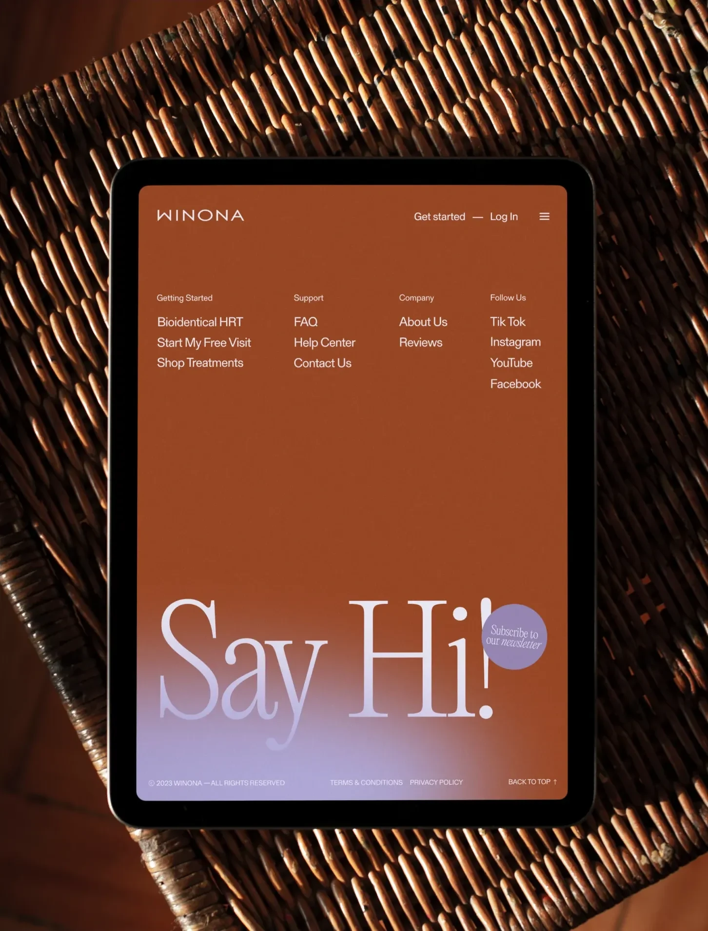 Winona website displayed on a tablet in a woven chair.