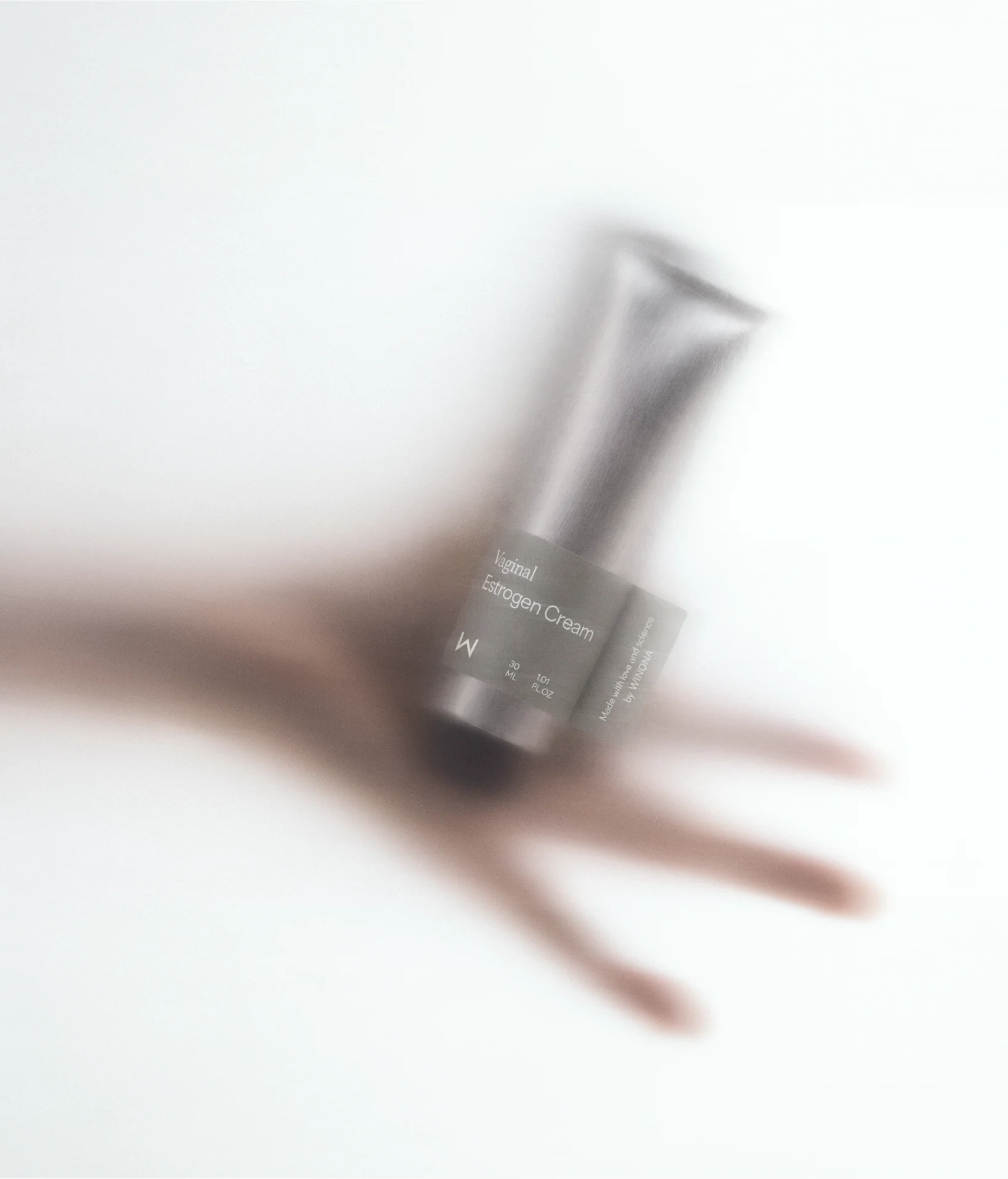 Blurred hand holding Winona estrogen cream.