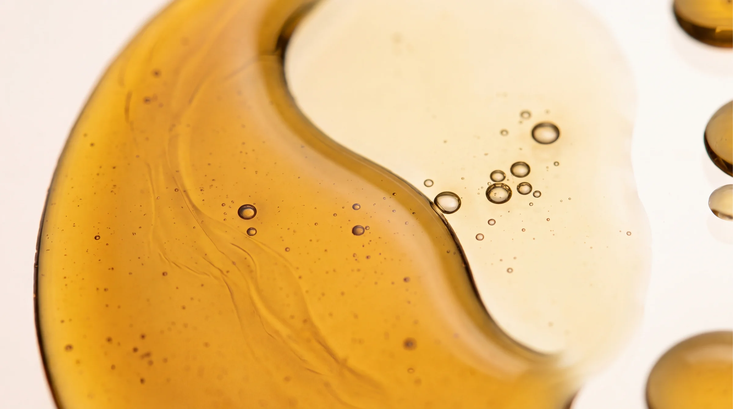 Golden serum spreading across a pale surface with tiny bubbles.