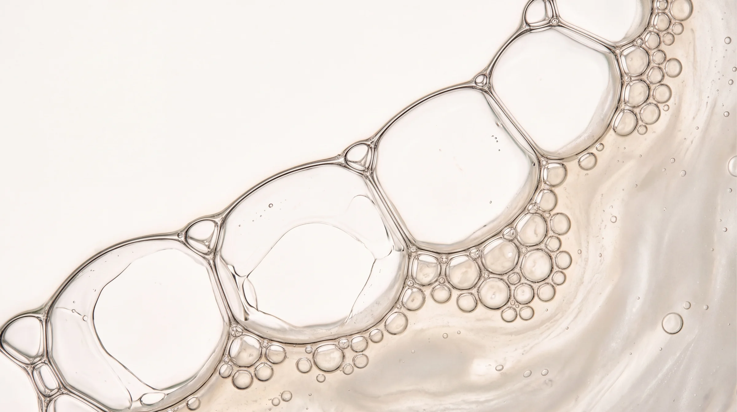 Chain of clear bubbles over a milky, creamy texture.