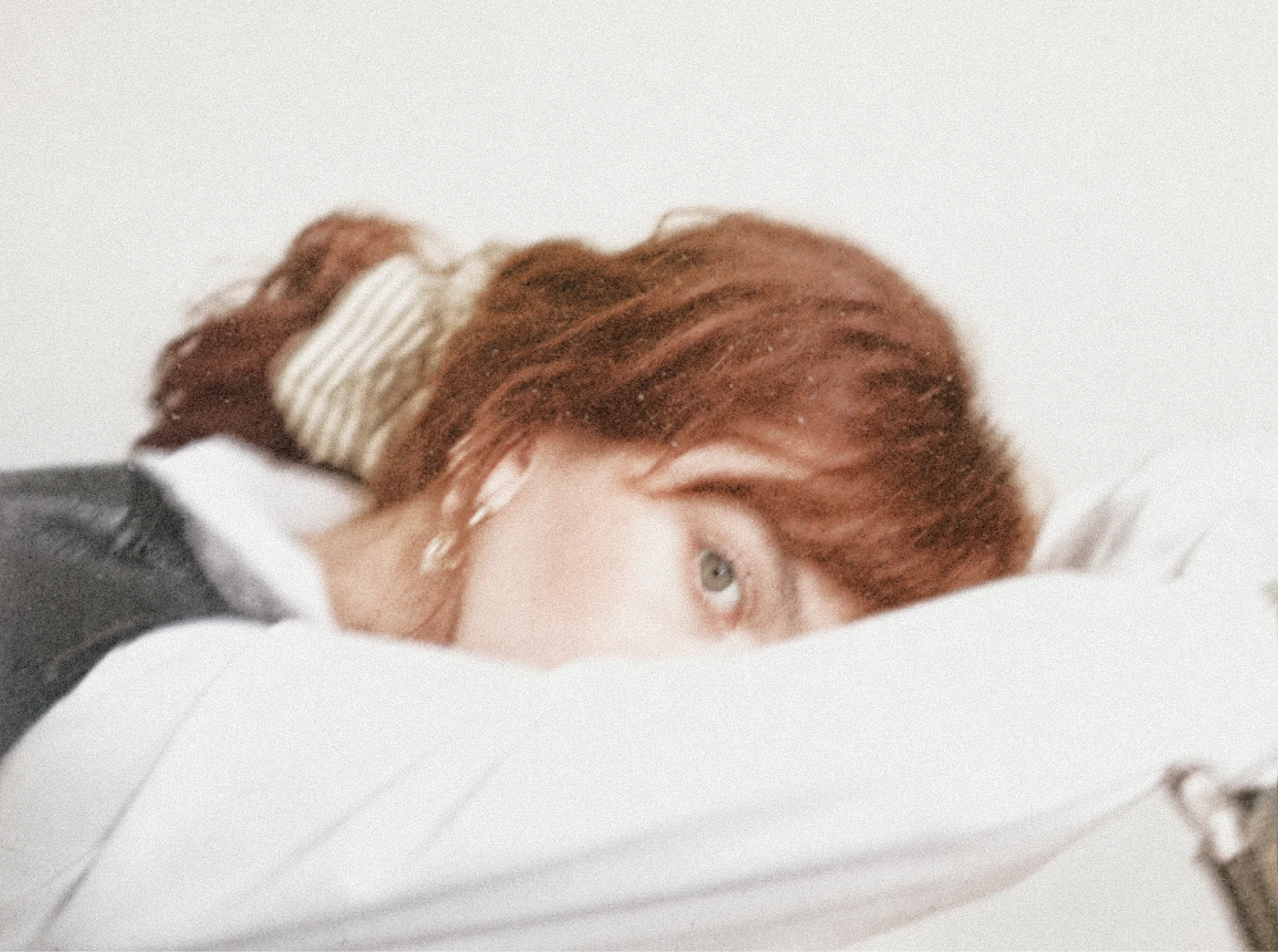 Micaela resting with her face partly hidden by a white duvet.