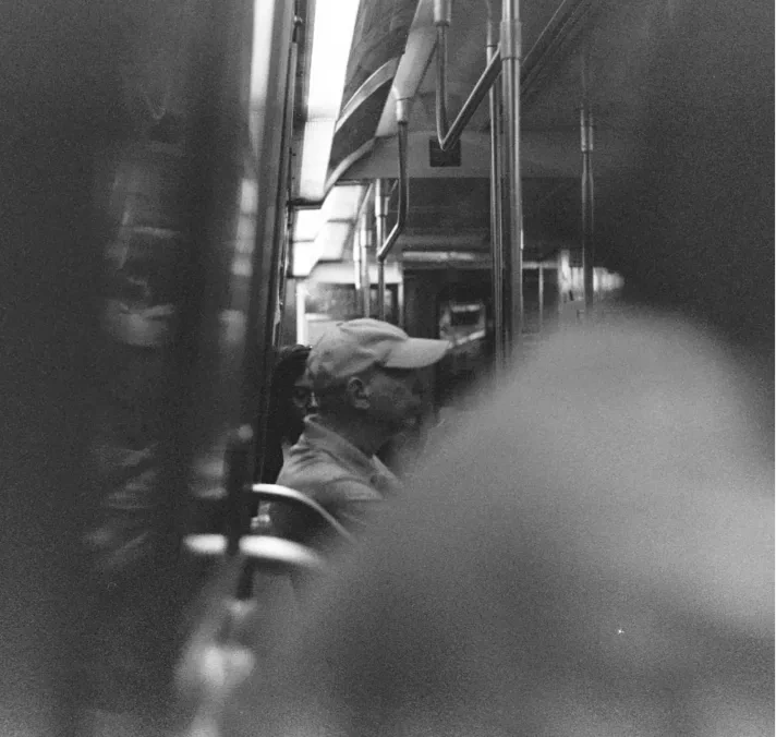 A subway passenger reflected in a black-and-white train window.