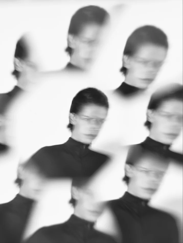 Blurred black-and-white portrait repeated across the frame.