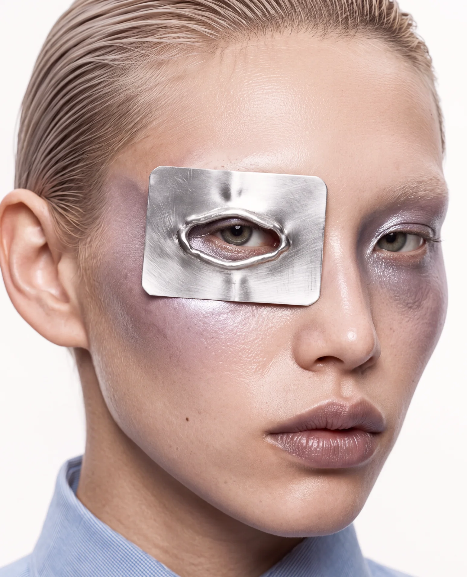 Face with a polished silver plate over one eye and lilac sheen on the skin.
