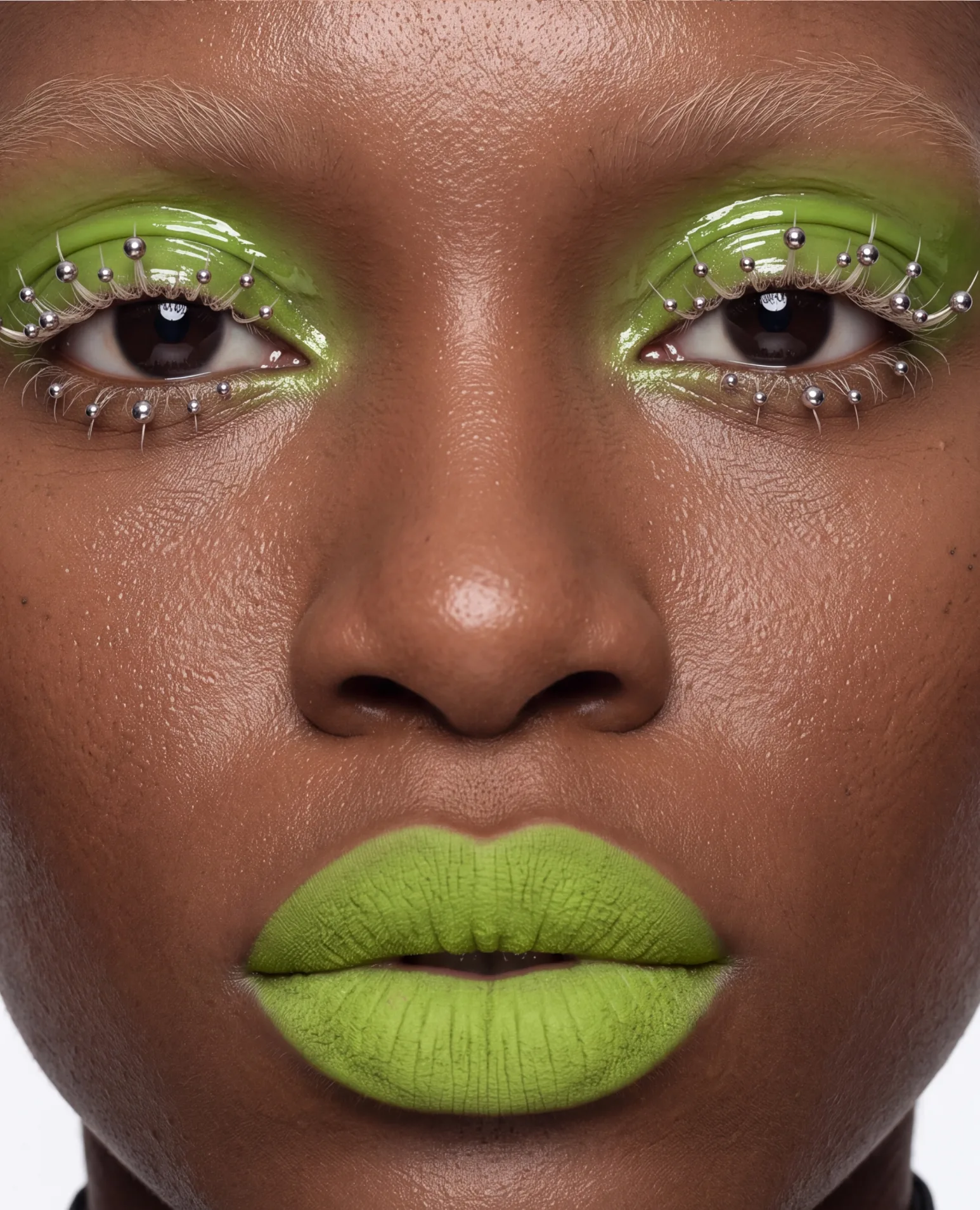 Glossy lime-green lids lined with silver studs and matching lips.