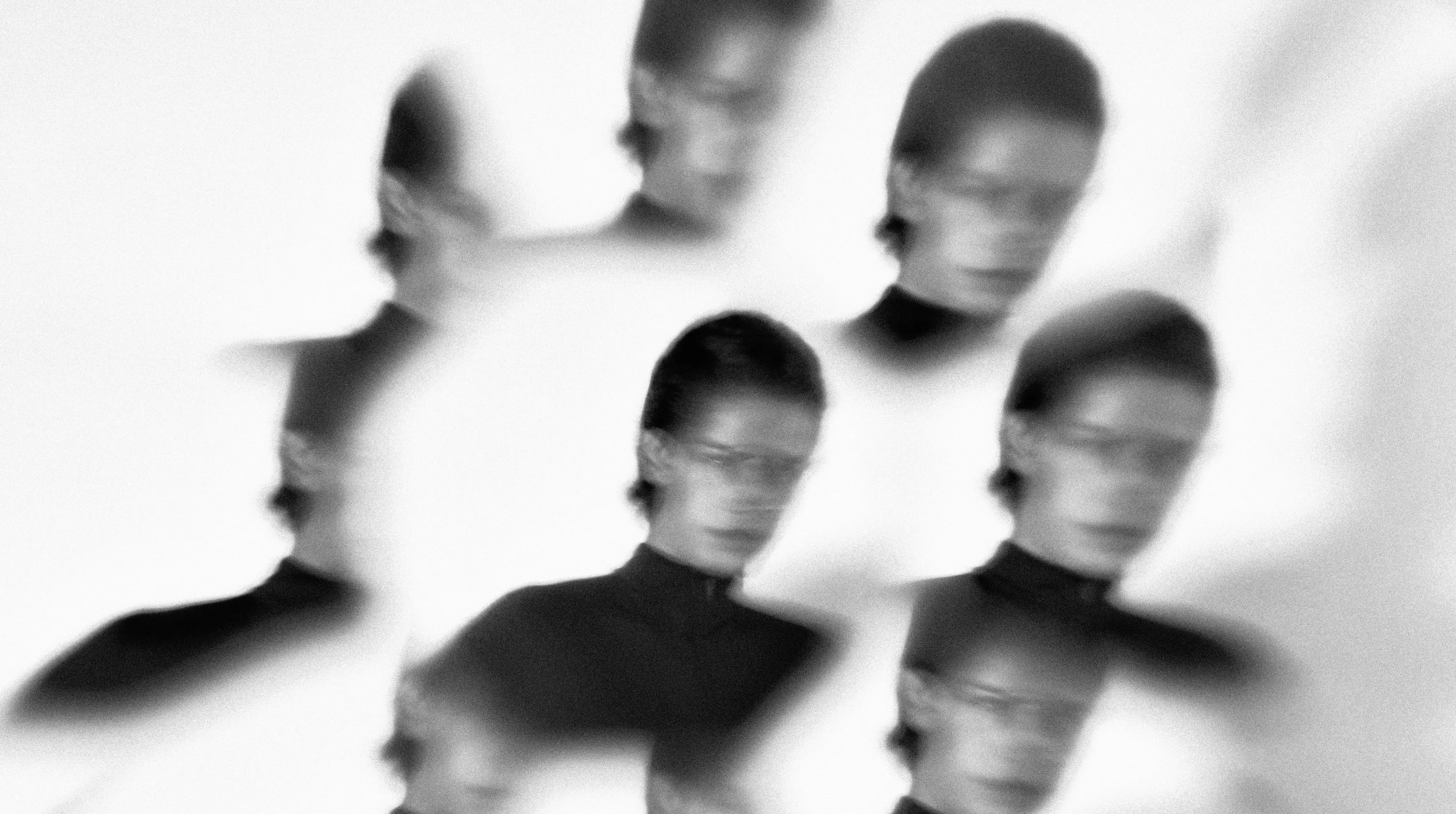 Black-and-white portraits in white high-neck suits repeated and blurred across a pale wall.