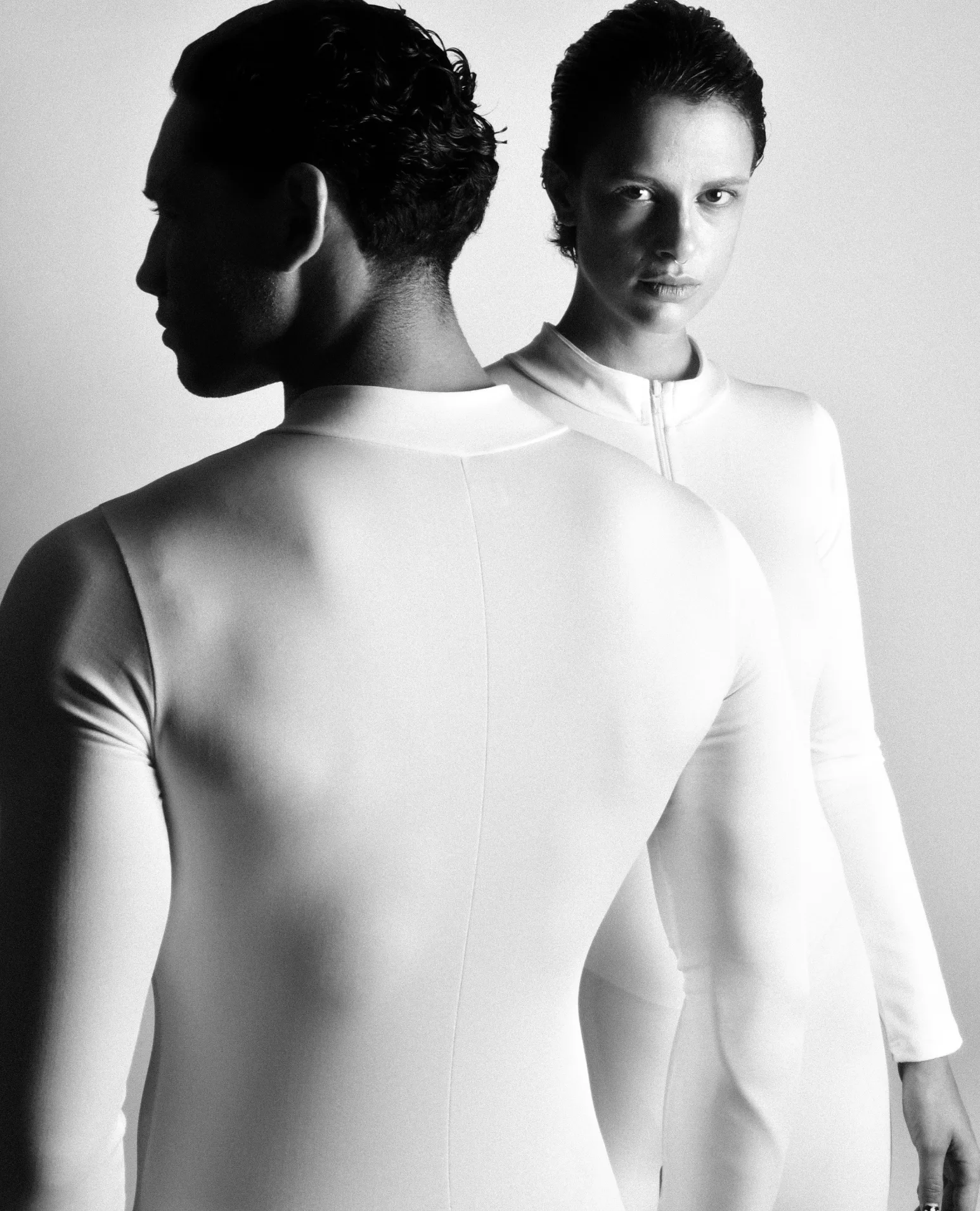 Two figures in white suits, one turned away, the other looking over his shoulder.