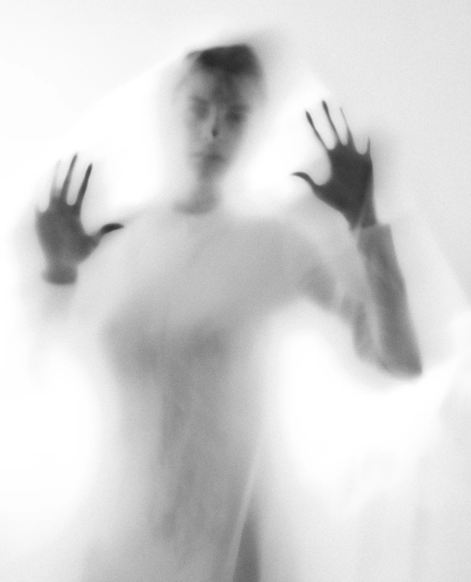 A figure behind a sheet of frosted plastic, hands pressed against it.