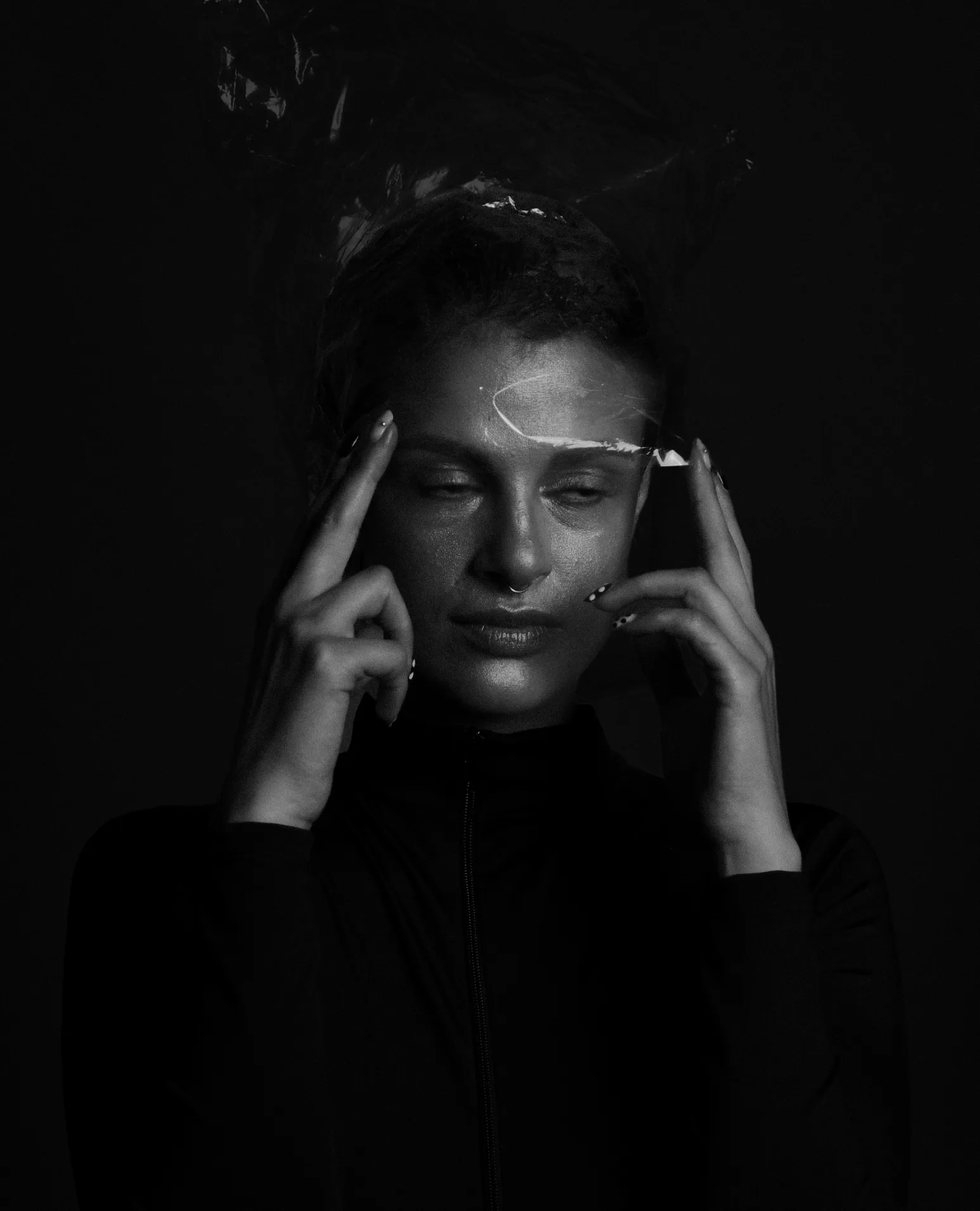 A woman with her fingers to her temples, plastic shining in her hair.